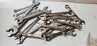 Photo of multiple open end combination wrenches in various sizes, some with surface rust and wear