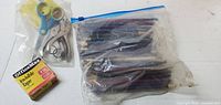 Photo showing a boxed roll of OfficeMax Invisible Tape, a pair of yellow and green handled scissors, a metal and black staple remover, and a large ziplock bag holding many used pencils.