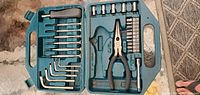 Open blue plastic tool case showing contents: hex keys, sockets, pliers, screwdriver bits, and handle extension.
