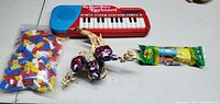Photo showing the My Music Maker keyboard, a large bag of assorted plastic building blocks, skeletal dinosaur figure, and a PEZ candy dispenser.