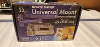 Box showing front and side views of the Space Saver Universal Mount in original packaging, detailing compatibility and weight limits.