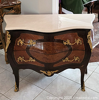 Front view showing white marble top, bombe front and ornate gilt ormolu accents