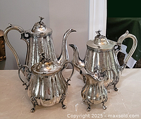 Full view of the antique silver plated tea and coffee set showing four pieces arranged on a marble surface.