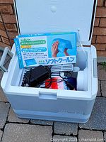 White Igloo cooler with hinged lid open, showing black power adapter cord and cooling gel ice pack inside