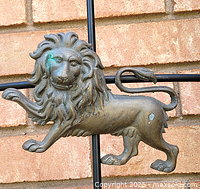 Full view of brass lion wall art showing weathering and patina.