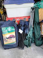 Four folding camping chairs folded and stored in dark fabric carrying bags.