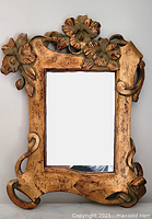 Front view of the gilt wood mirror showing the carved floral and leaf design around the frame and the glass reflective surface.