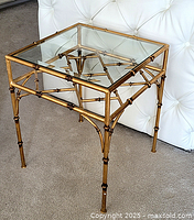 Front three-quarter view of end table showing clear glass top and bamboo-style metal frame