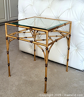 Front right three-quarter view of gold metal bamboo motif end table with glass top