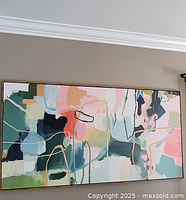 Framed large abstract art print hanging on wall showing full artwork and wooden frame.