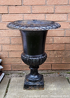 Front view of large cast iron planter urn showing its size, shape and decorative scalloped rim.