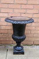 Full front view showing the overall shape and design of the large black cast iron urn planter
