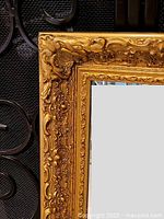 Close-up of the ornate gold frame showing detailed floral and scroll carving