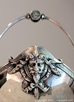 Close-up photo showing detailed face decoration on the side of the silver plated basket.