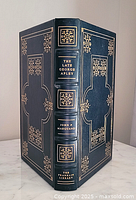 Front and spine view of the book showing gold embossed title and decorative patterns on dark blue leather binding.