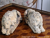 Pair of stone molded lion bookends shown side by side on a checkered wooden table.