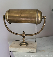 Front view of lamp showing brass cylinder shade atop marble base