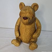 Front view of the Winnie the Pooh resin figurine showing wooden texture and paint details.