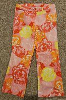 Front view of Lilly Pulitzer floral pants showing the full length with large floral print in pink, orange, yellow, and white.