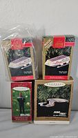 Four Hallmark Keepsake Star Trek-themed Christmas ornaments in their original boxes, two Magic ornaments and two standard character/starship ornaments.