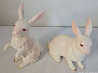 Pair of two vintage Lefton rabbit figurines, one standing and one sitting, displayed together on a white surface.