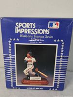 Blue box with stars and white text showing the front of the Sports Impressions Willie Mays figurine box and the image of the figurine.