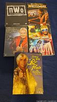Five wrestling DVD cases arranged in two rows. Top row: nWo The Revolution, WrestleMania The True Story. Bottom row: Bobby Heenan, Randy Savage, Ric Flair Collection.