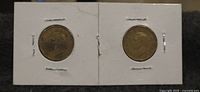 Obverse sides of both coins in cardboard holders