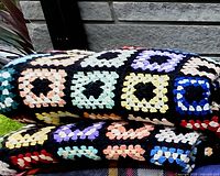 Both folded afghans showing multicoloured granny squares and black borders