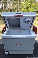 Cooler with lid open showing interior and lid-mounted cooling module, wheels visible