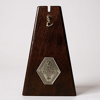Front view of wooden Maelzel Paquet metronome showing plaque and hook