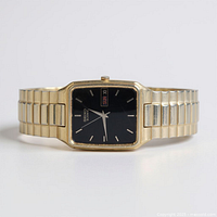 Front view of Seiko gold-tone quartz watch showing black dial, day-date, expansion band