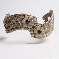 Oblique view showing floral engraving, three stones, cuff shape