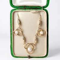Necklace in box showing full design with three pearl loop motifs and oval gold beads