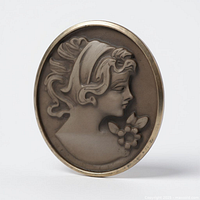 Front view of oval cameo showing woman’s profile and floral detail within gold bezel.