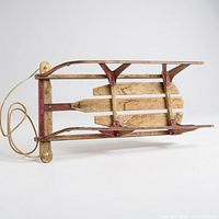 Underside view of vintage wooden sled showing slats, red metal runners, cross braces and pull rope