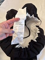 Photo of the label tag on the cozy carrier cover indicating materials and brand details, showing 100% polyester covering, filling and backing.