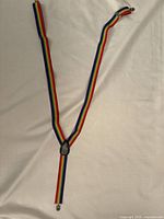 Rainbow-striped Pride suspenders laid out flat on white background showcasing full length and clip ends.