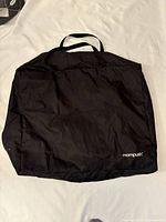 Black Mompush travel stroller carry bag on white surface, showing front side with logo