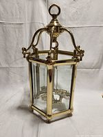 Brass lantern front view showing hexagonal shape, brass frame, glass panels, and internal candle holders