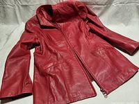 Full view of red women's leather jacket laid flat to show design and condition.