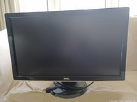 Front view of Dell ST2410b monitor showing the screen and base stand with power cable wound around it.