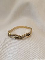 Ring on white fabric background showing entwined wave pattern and diamond detail