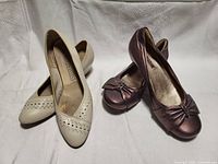 Two pairs of women's shoes: ECCO white flats and NATURALIZER purple pumps side by side on white background.