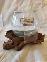 Front view of clear handblown molten glass bowl on natural wood base with label showing origin