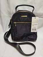 Front view of the black mini convertible backpack with tag attached.