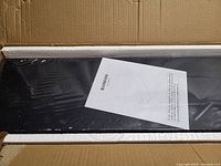 Two black floating shelves in original packaging with BAMIEOS instruction sheet on top.