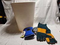 Photo showing a large white planter and one pair of garden gloves alongside blue knee pads