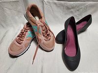 Pair of pink and teal Saucony women's running shoes size 6 and one pair of black Crocs women's shoes size 7 on white background