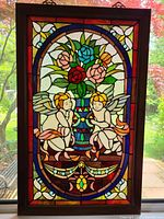 Full view of the stained glass angel panel in wooden frame, showing entire colorful design featuring two angels and floral bouquet.